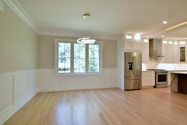 kitchen with white cabinets, wall chimney exhaust hood, light wood finished floors, high end appliances, and glass insert cabinets