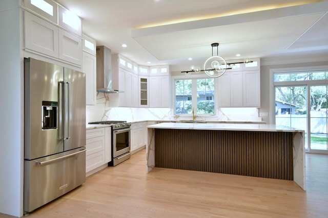 kitchen featuring stainless steel appliances, plenty of natural light, backsplash, and wall chimney exhaust hood