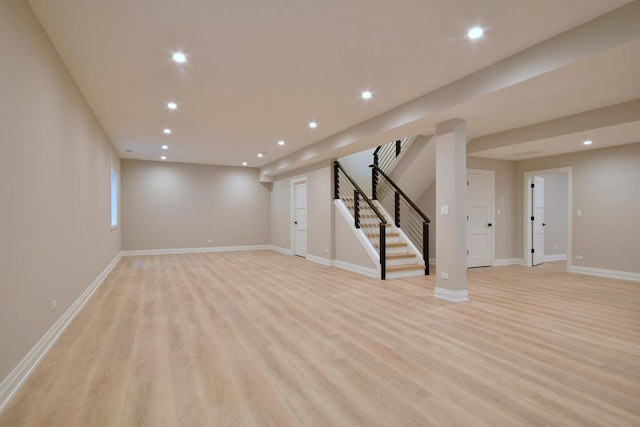 below grade area with light wood finished floors, stairs, baseboards, and recessed lighting