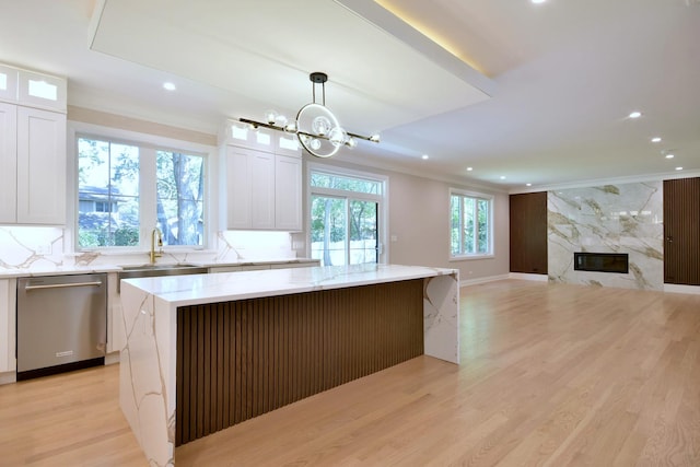 kitchen with a healthy amount of sunlight, a fireplace, stainless steel dishwasher, and a center island