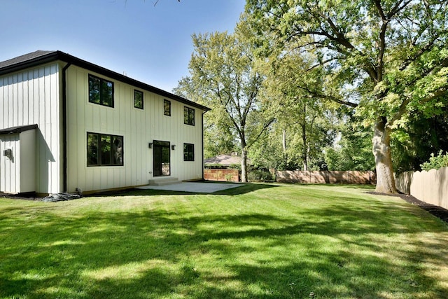 back of property featuring a yard, board and batten siding, a patio area, and a fenced backyard