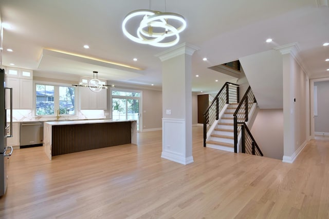 kitchen with a chandelier, light countertops, stainless steel dishwasher, a center island, and decorative columns