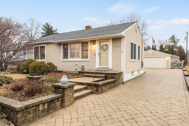 view of front of house featuring an outbuilding, roof with shingles, a chimney, and a garage