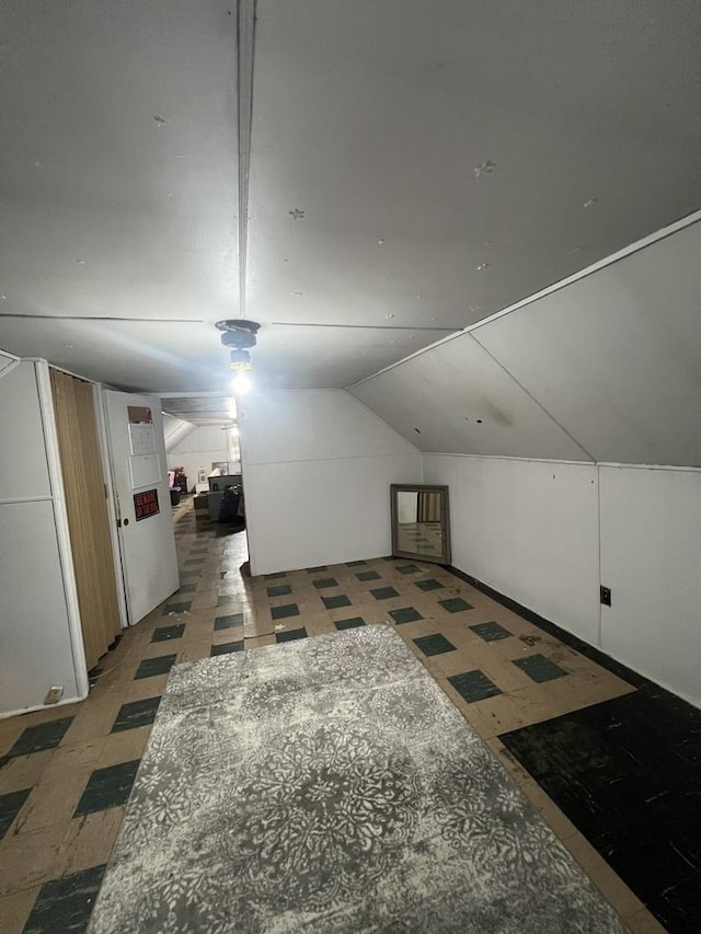 additional living space featuring vaulted ceiling and tile patterned floors