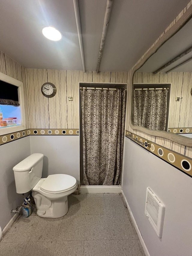 bathroom featuring curtained shower, beam ceiling, toilet, and baseboards