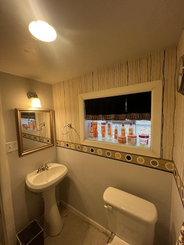 bathroom with a sink, toilet, and baseboards