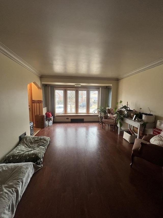 living area with arched walkways, crown molding, and wood finished floors