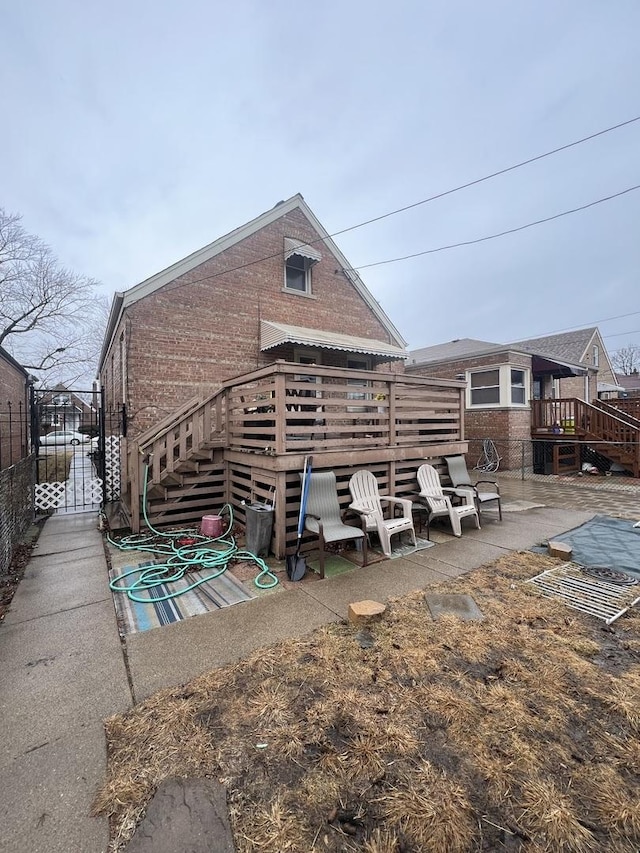 back of house featuring a patio area, a deck, and brick siding