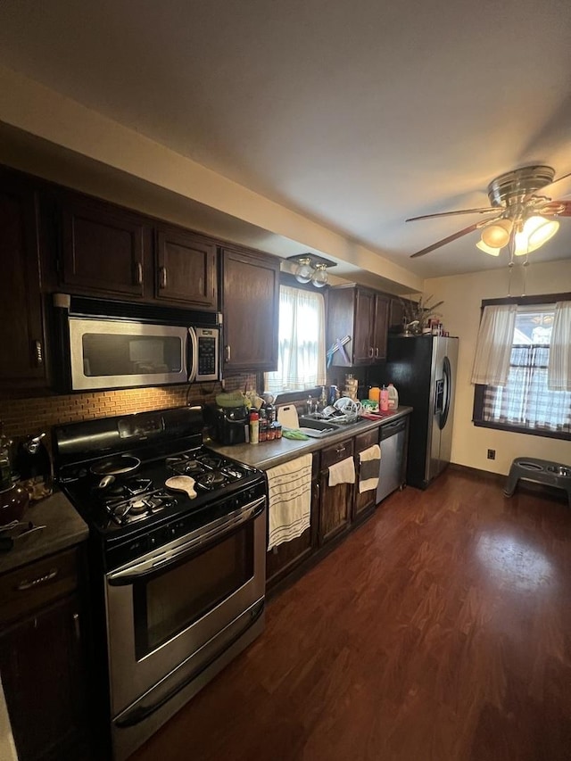 kitchen featuring dark wood-style flooring, baseboards, dark brown cabinets, appliances with stainless steel finishes, and decorative backsplash