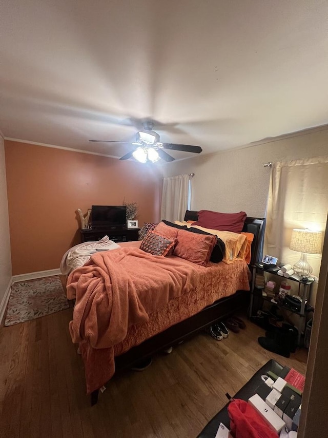 bedroom featuring ceiling fan, baseboards, and wood finished floors