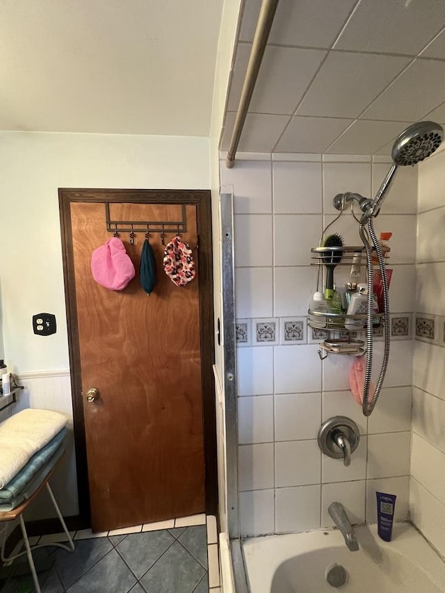 bathroom with a wainscoted wall, tile patterned flooring, and shower / washtub combination