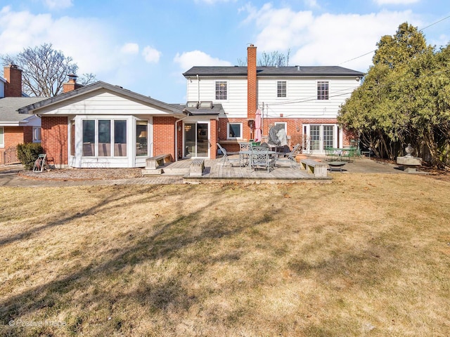 back of property featuring a yard, brick siding, and a chimney