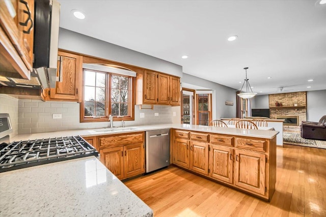 kitchen with open floor plan, dishwasher, a fireplace, a peninsula, and a sink