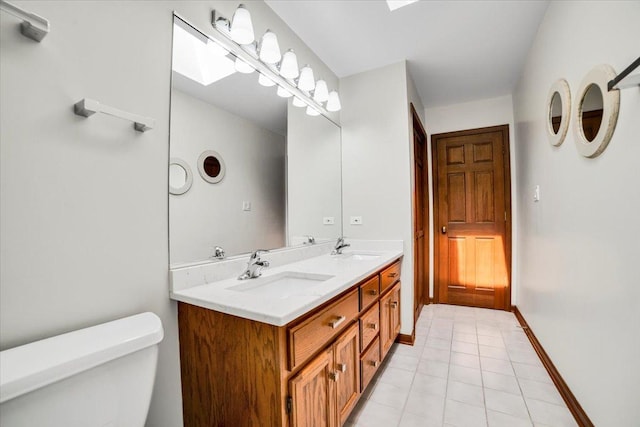 bathroom featuring a sink, toilet, a skylight, and tile patterned flooring