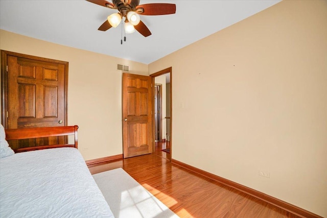 bedroom with visible vents, baseboards, a ceiling fan, and light wood finished floors