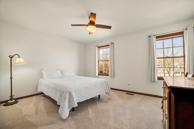 bedroom featuring multiple windows, light colored carpet, visible vents, and baseboards