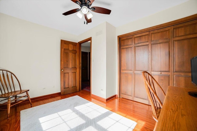 office space with visible vents, baseboards, a ceiling fan, and light wood finished floors