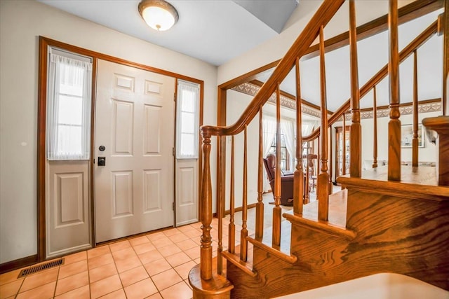 entryway featuring stairs, light tile patterned flooring, visible vents, and a wealth of natural light