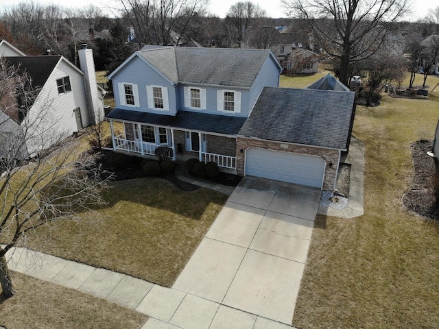 traditional home featuring a front lawn, roof with shingles, covered porch, a garage, and driveway