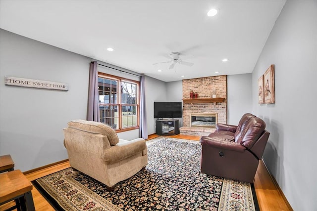 living area with wood finished floors, baseboards, recessed lighting, a fireplace, and ceiling fan