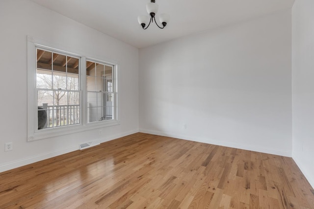 unfurnished room with visible vents, light wood-style flooring, and baseboards