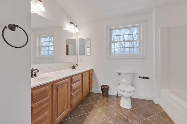 bathroom with double vanity, a sink, toilet, and tile patterned floors