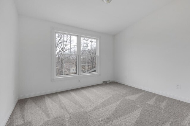 carpeted spare room with visible vents and baseboards