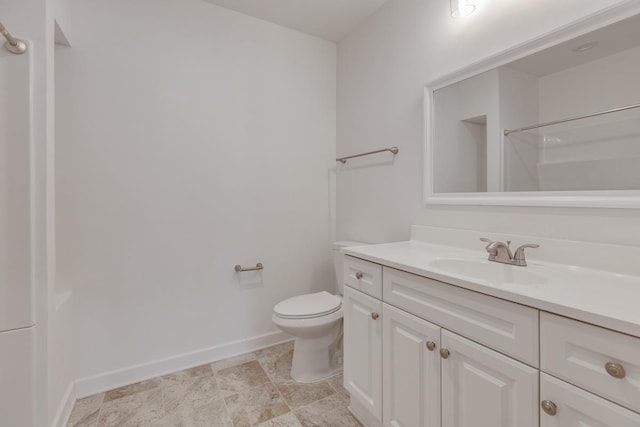 bathroom with baseboards, vanity, toilet, and walk in shower