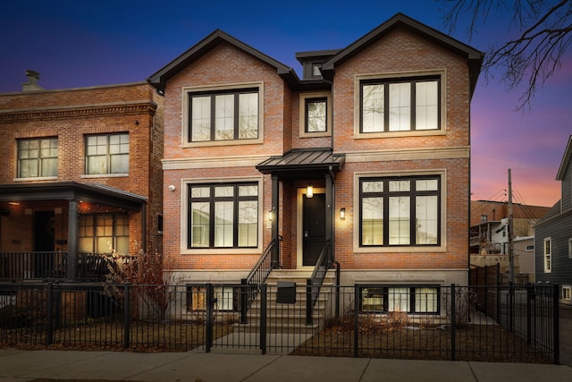 townhome / multi-family property featuring a fenced front yard, entry steps, a standing seam roof, and brick siding