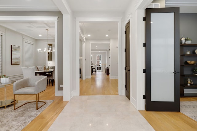 foyer entrance with light wood finished floors, coffered ceiling, recessed lighting, and an inviting chandelier