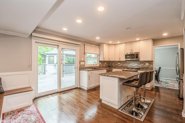 kitchen featuring a center island, tasteful backsplash, appliances with stainless steel finishes, white cabinets, and a sink