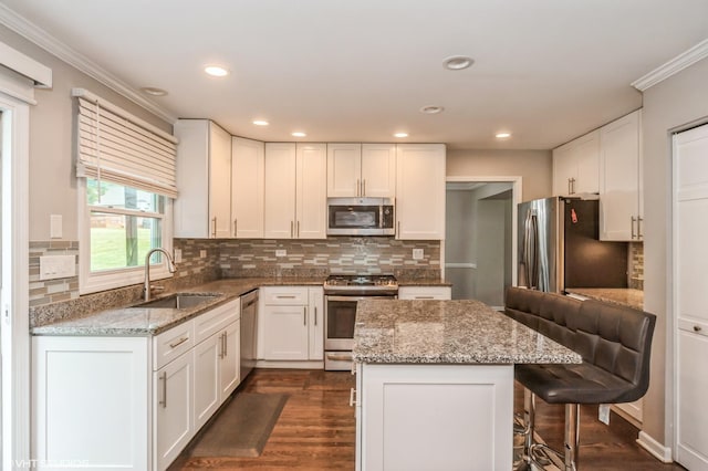 kitchen with white cabinetry, appliances with stainless steel finishes, a sink, and a center island