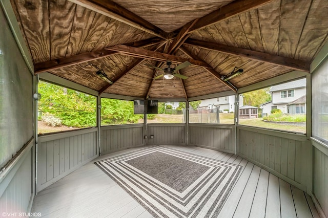 unfurnished sunroom with ceiling fan, wooden ceiling, and vaulted ceiling with beams