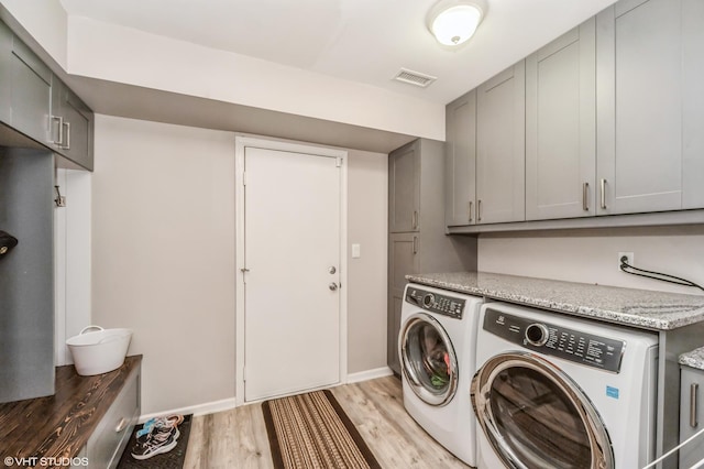 washroom with washing machine and clothes dryer, visible vents, cabinet space, light wood-type flooring, and baseboards