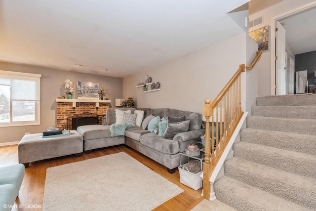 living area featuring visible vents, a fireplace, stairway, and wood finished floors