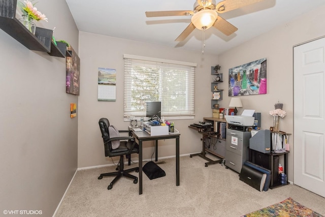 carpeted office space featuring ceiling fan and baseboards