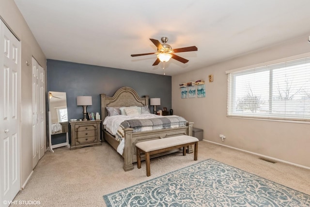 bedroom featuring light carpet, a ceiling fan, visible vents, and baseboards