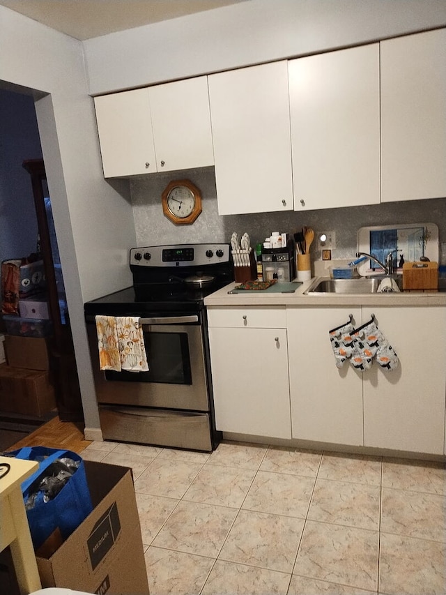 kitchen with electric stove, tasteful backsplash, light countertops, white cabinetry, and a sink