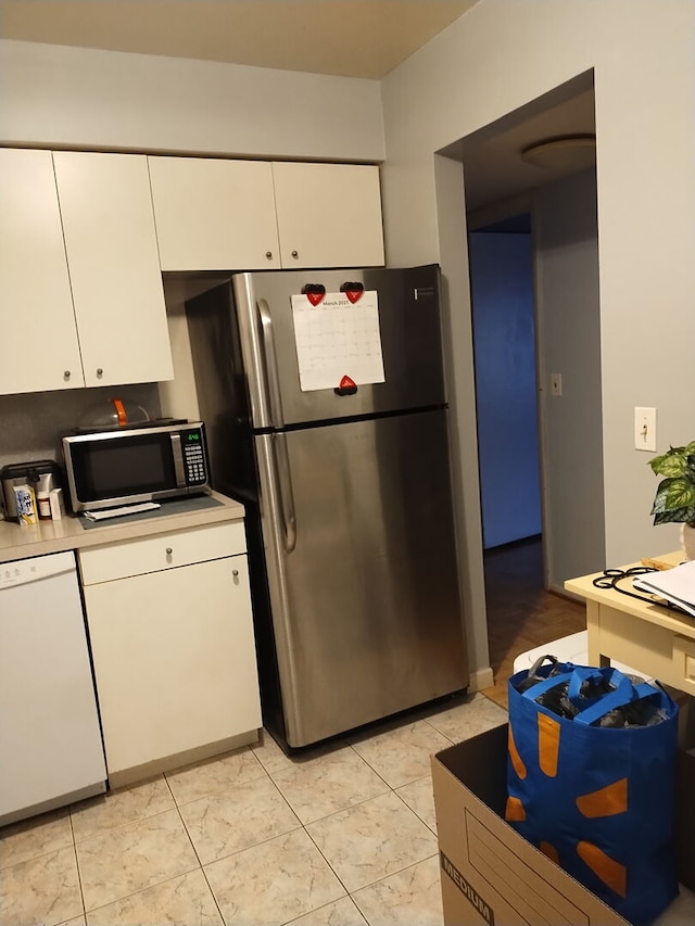 kitchen with stainless steel appliances, light tile patterned flooring, light countertops, and white cabinets