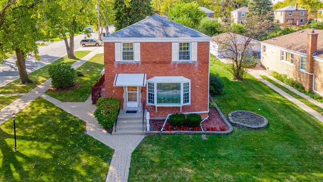 view of front of home with brick siding, roof with shingles, and a front yard