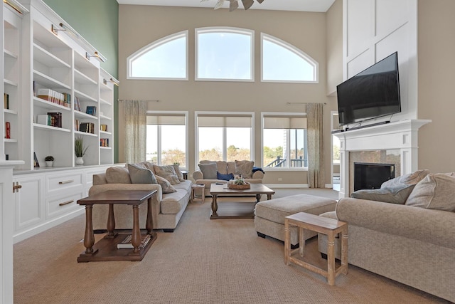 living room with a high ceiling, a fireplace, and light colored carpet