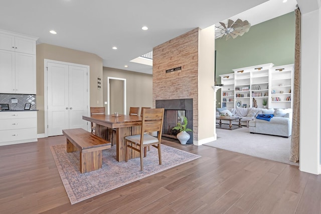 dining room with recessed lighting, baseboards, wood finished floors, and a stone fireplace