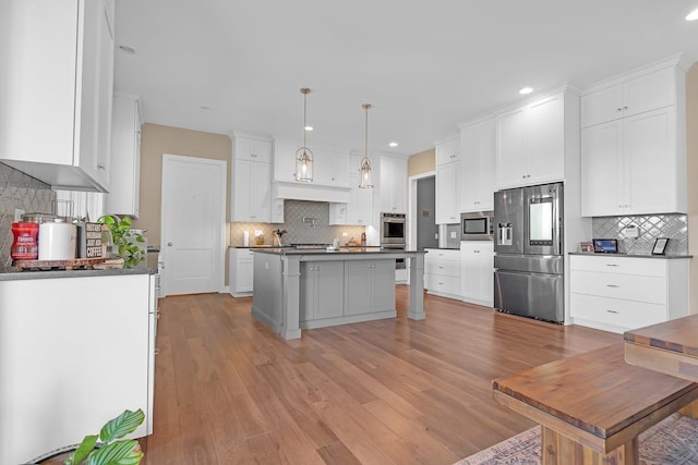 kitchen with stainless steel appliances, dark countertops, tasteful backsplash, a kitchen island, and light wood-type flooring