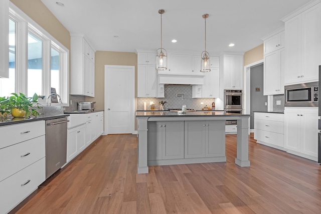 kitchen with appliances with stainless steel finishes, dark countertops, and light wood finished floors