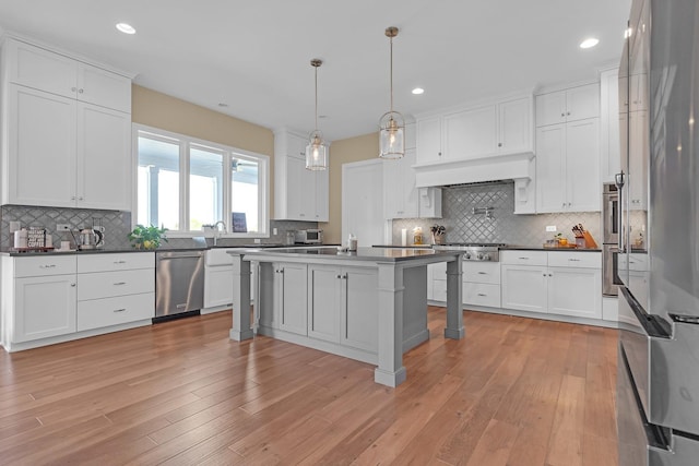 kitchen featuring dark countertops, light wood-style flooring, appliances with stainless steel finishes, and white cabinets