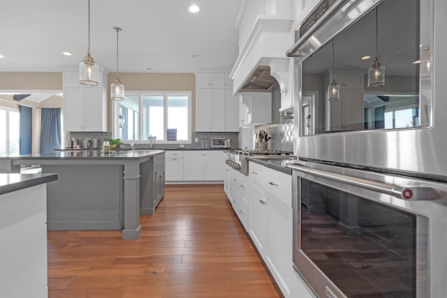 kitchen with dark countertops, hardwood / wood-style flooring, appliances with stainless steel finishes, and backsplash