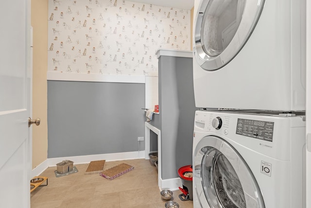 laundry room with stacked washer / dryer, laundry area, baseboards, and wallpapered walls