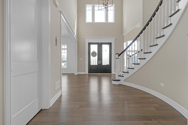 foyer with baseboards, wood finished floors, stairs, a high ceiling, and french doors