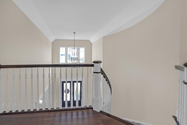 stairs with an inviting chandelier, high vaulted ceiling, and wood finished floors