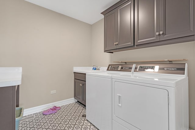 washroom featuring cabinet space, a sink, baseboards, and separate washer and dryer